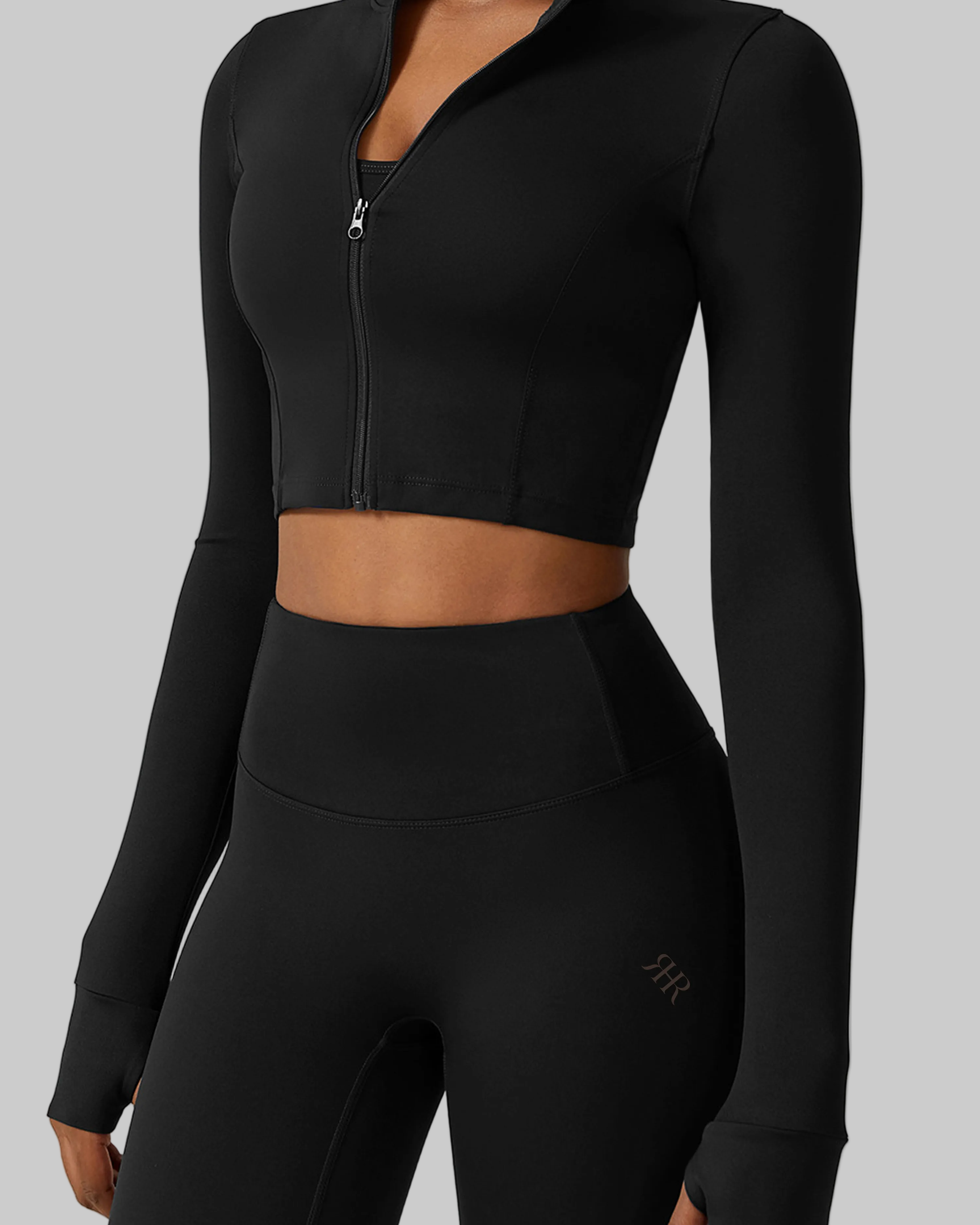 Black athletic outfit with long sleeves and high-waisted leggings on a white background