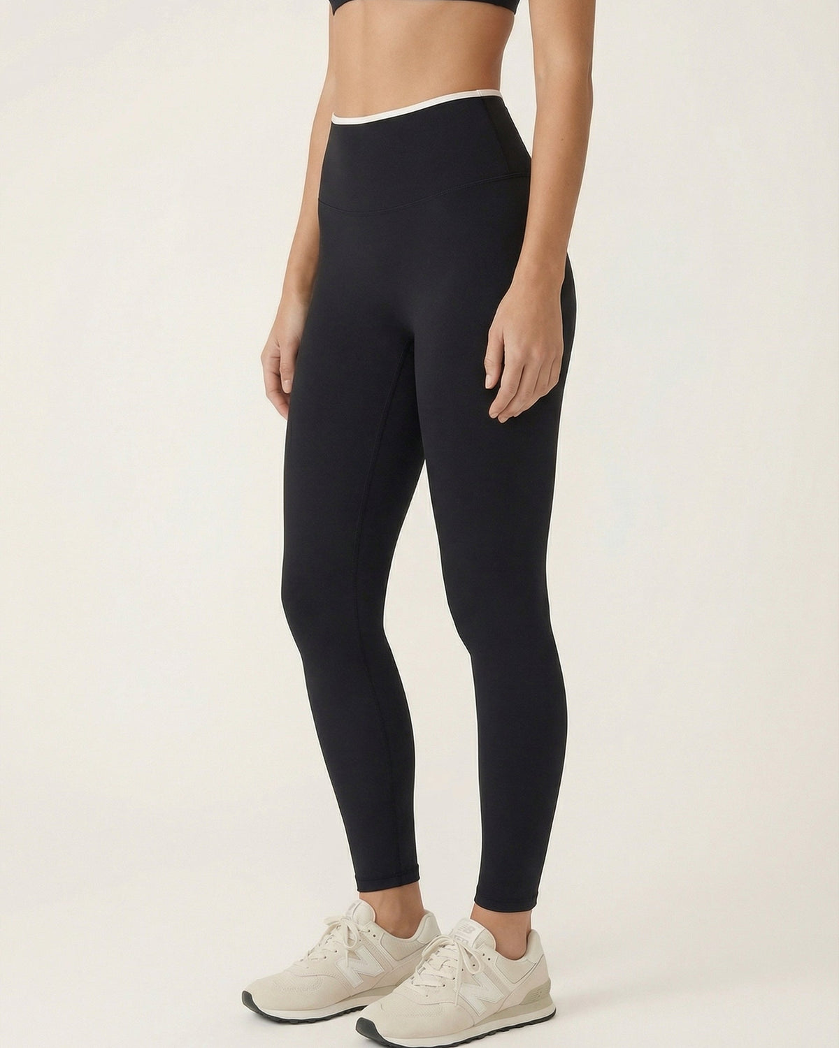 Person wearing black leggings and white sneakers on a plain background