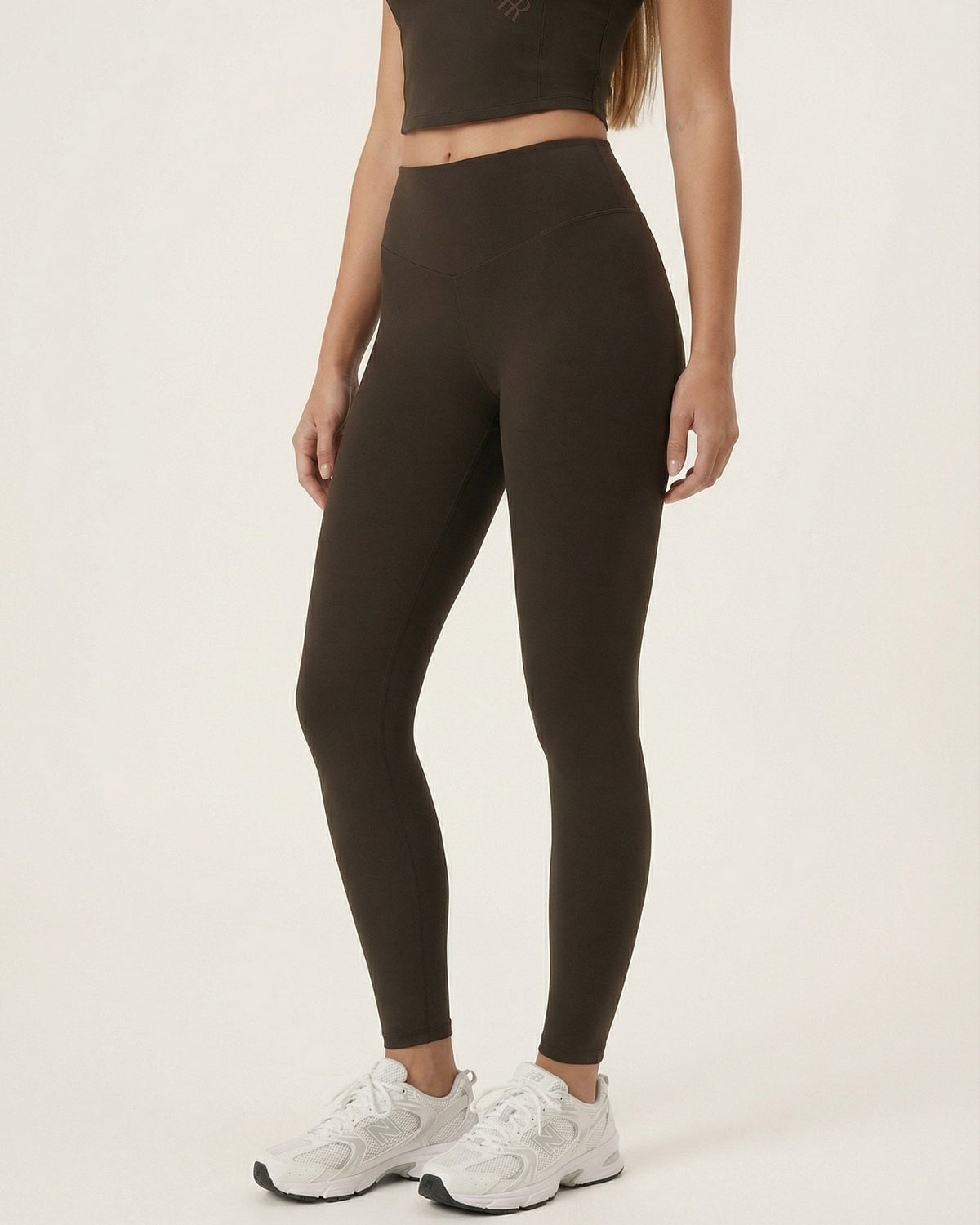 Person wearing black leggings and white sneakers on a plain background