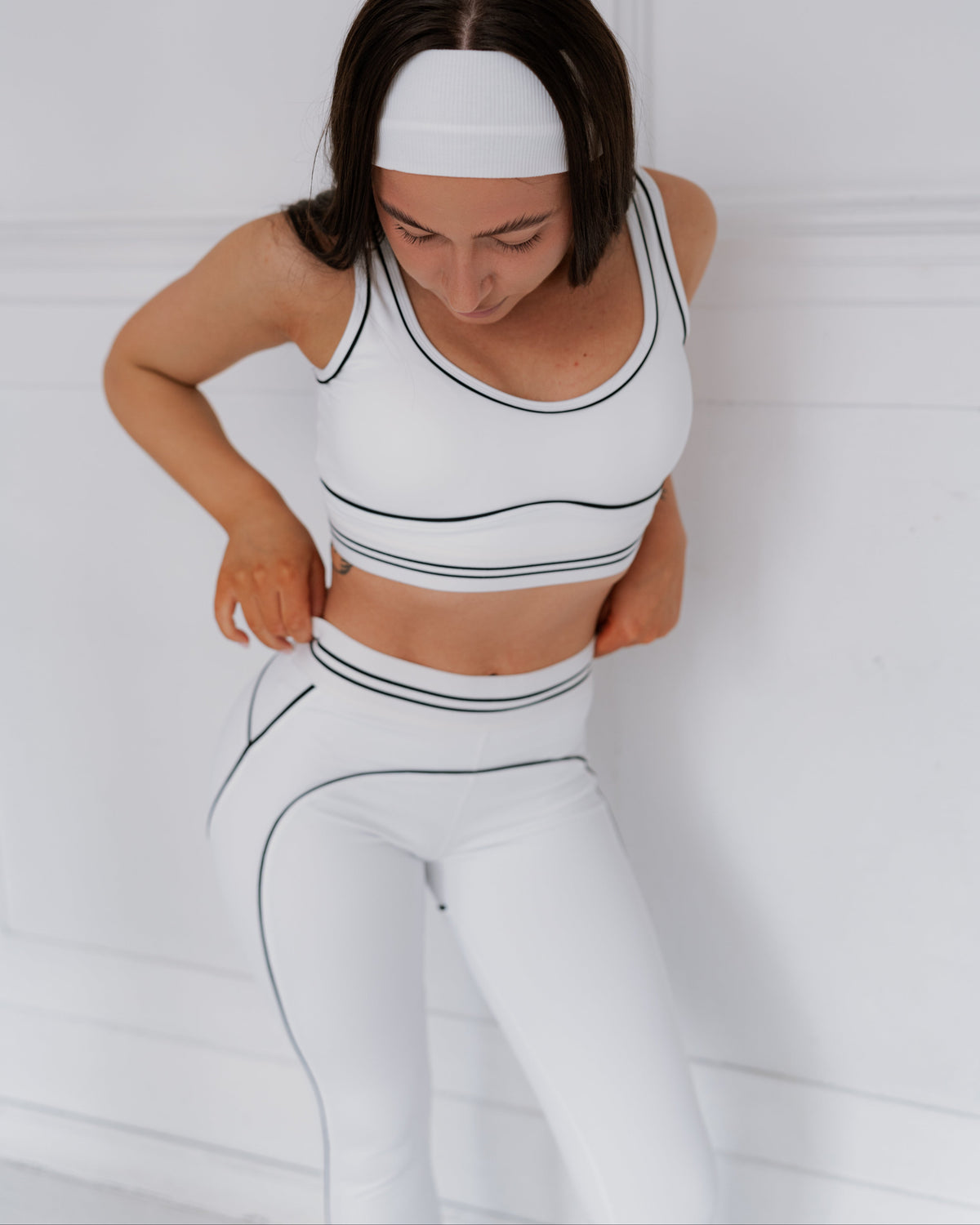 Woman wearing a white athletic outfit with black accents on a plain background