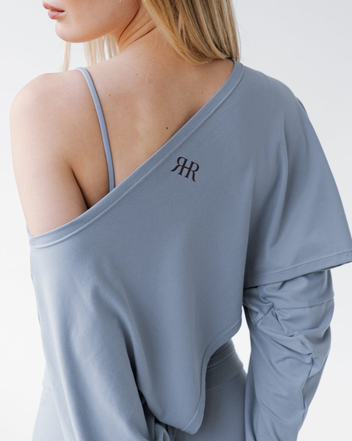 Light blue long-sleeve top with a brand logo on the back, worn by a person.