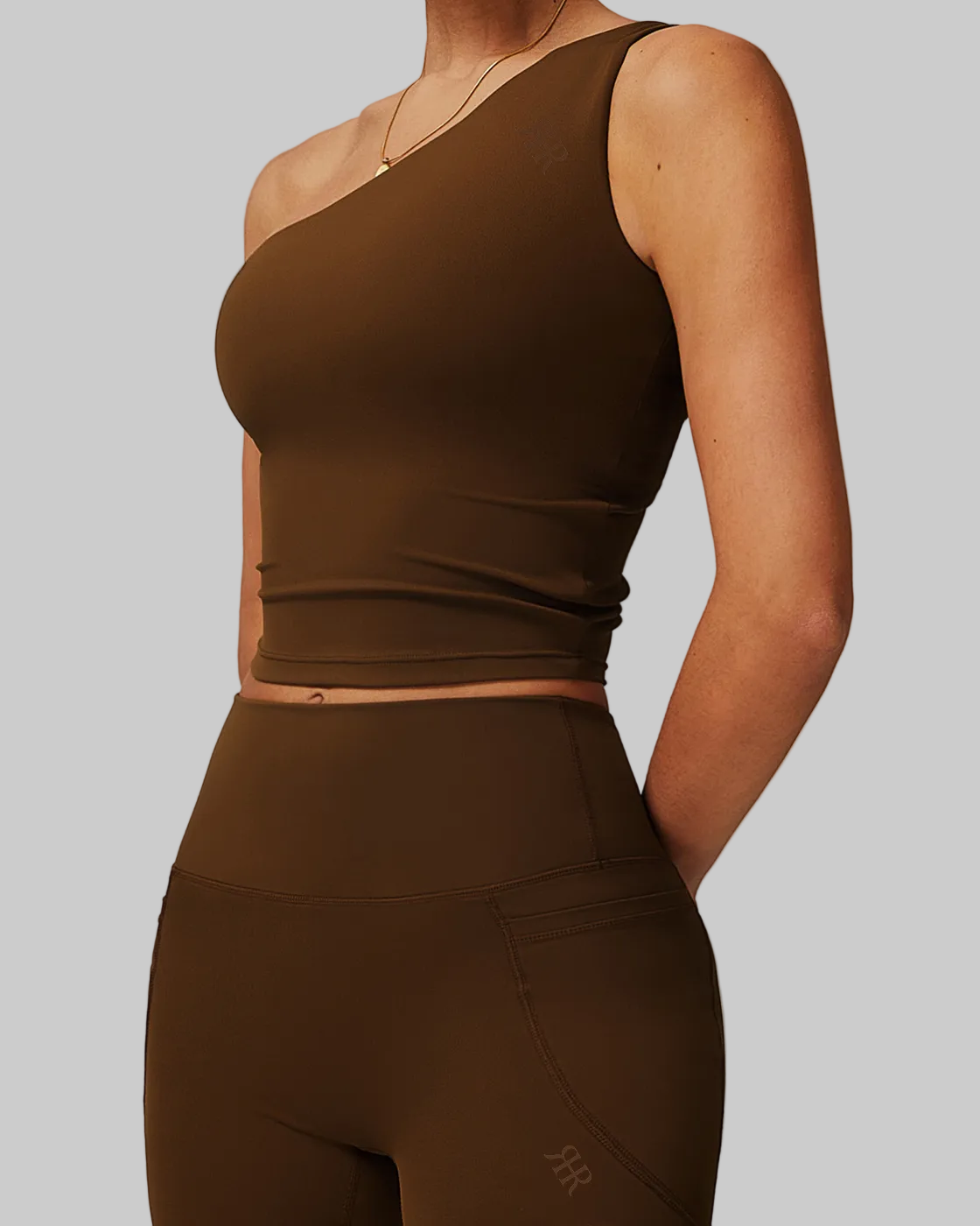 Brown athletic outfit with a crop top and shorts on a neutral background