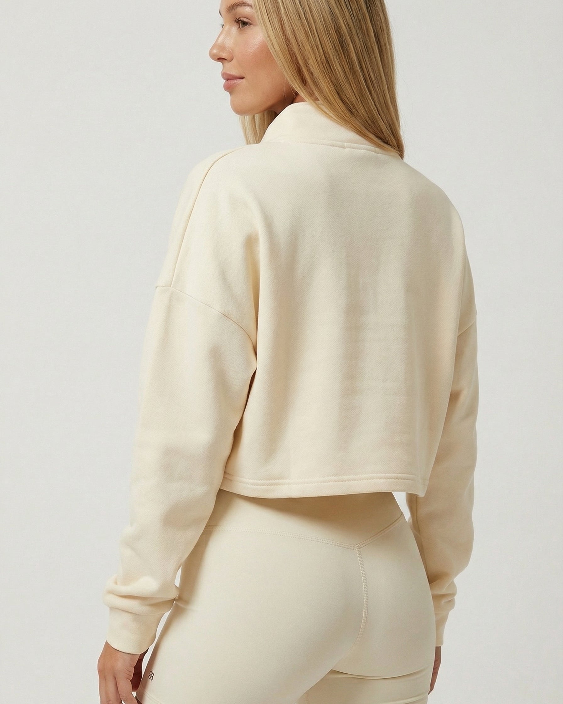 Woman wearing a beige tracksuit on a plain background