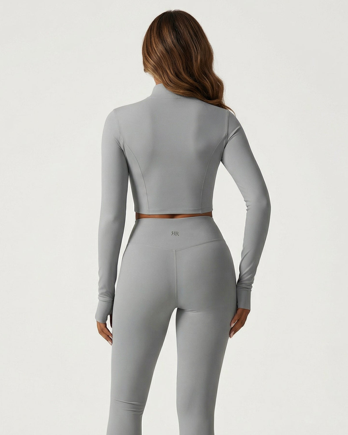 Person wearing a gray long-sleeve top and leggings on a white background