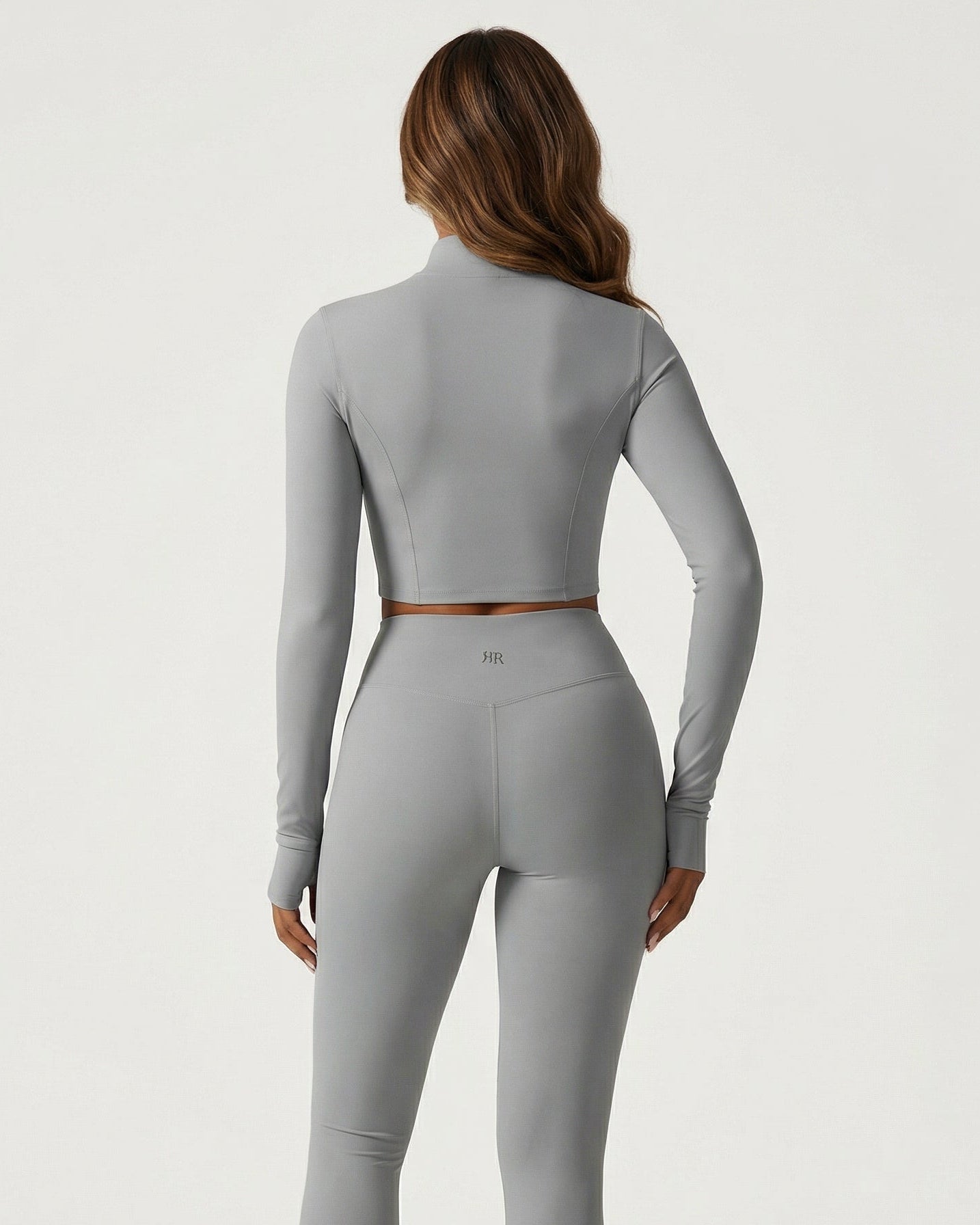 Person wearing a gray long-sleeve top and leggings on a white background