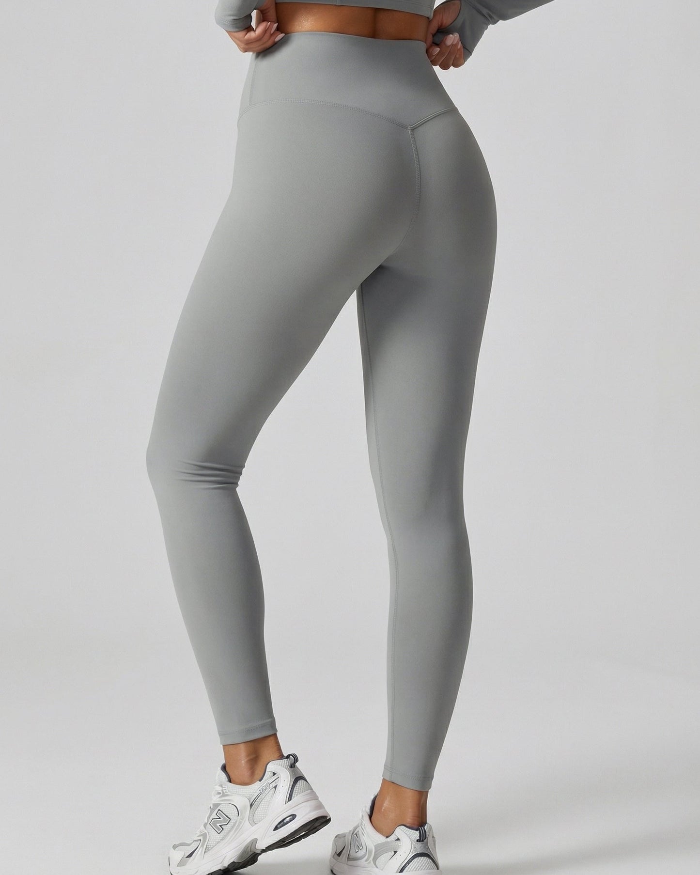 Person wearing gray leggings and white sneakers on a light gray background