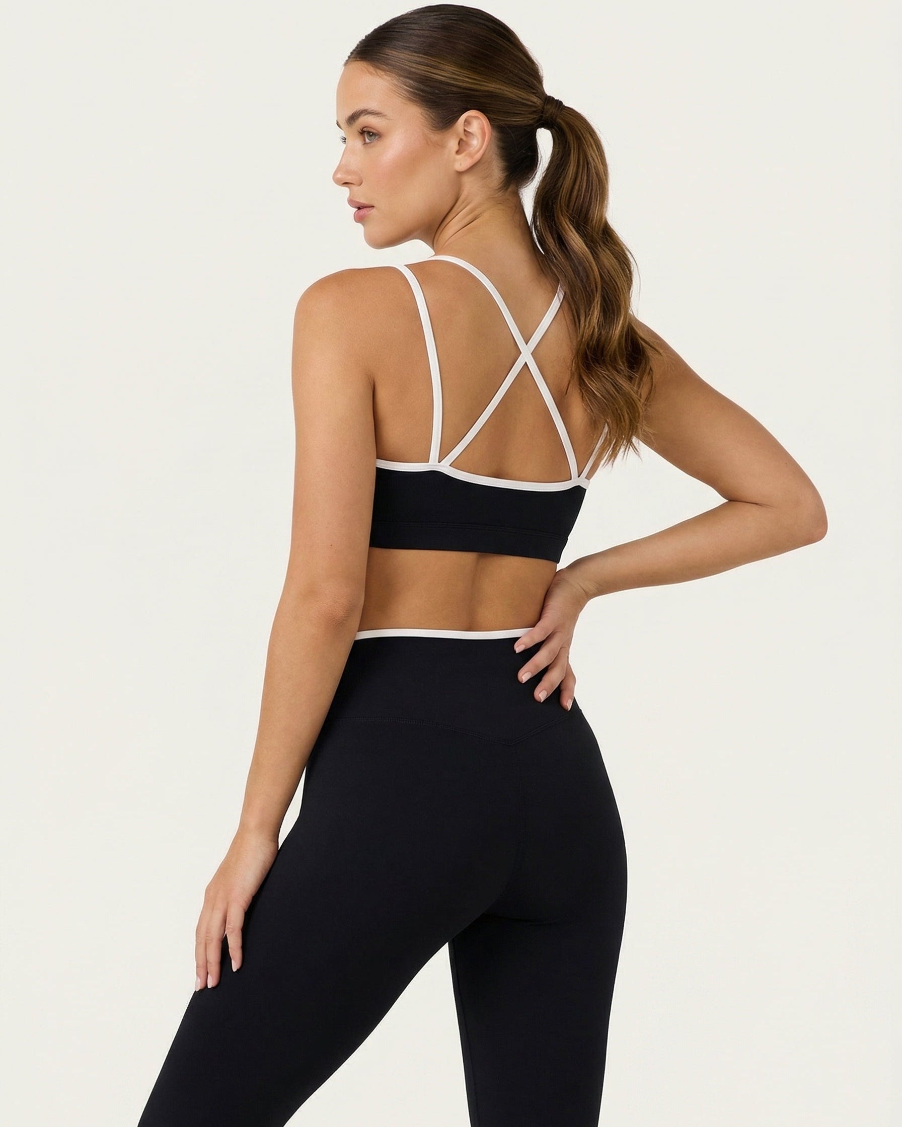 Woman wearing a black sports bra and leggings with a white background