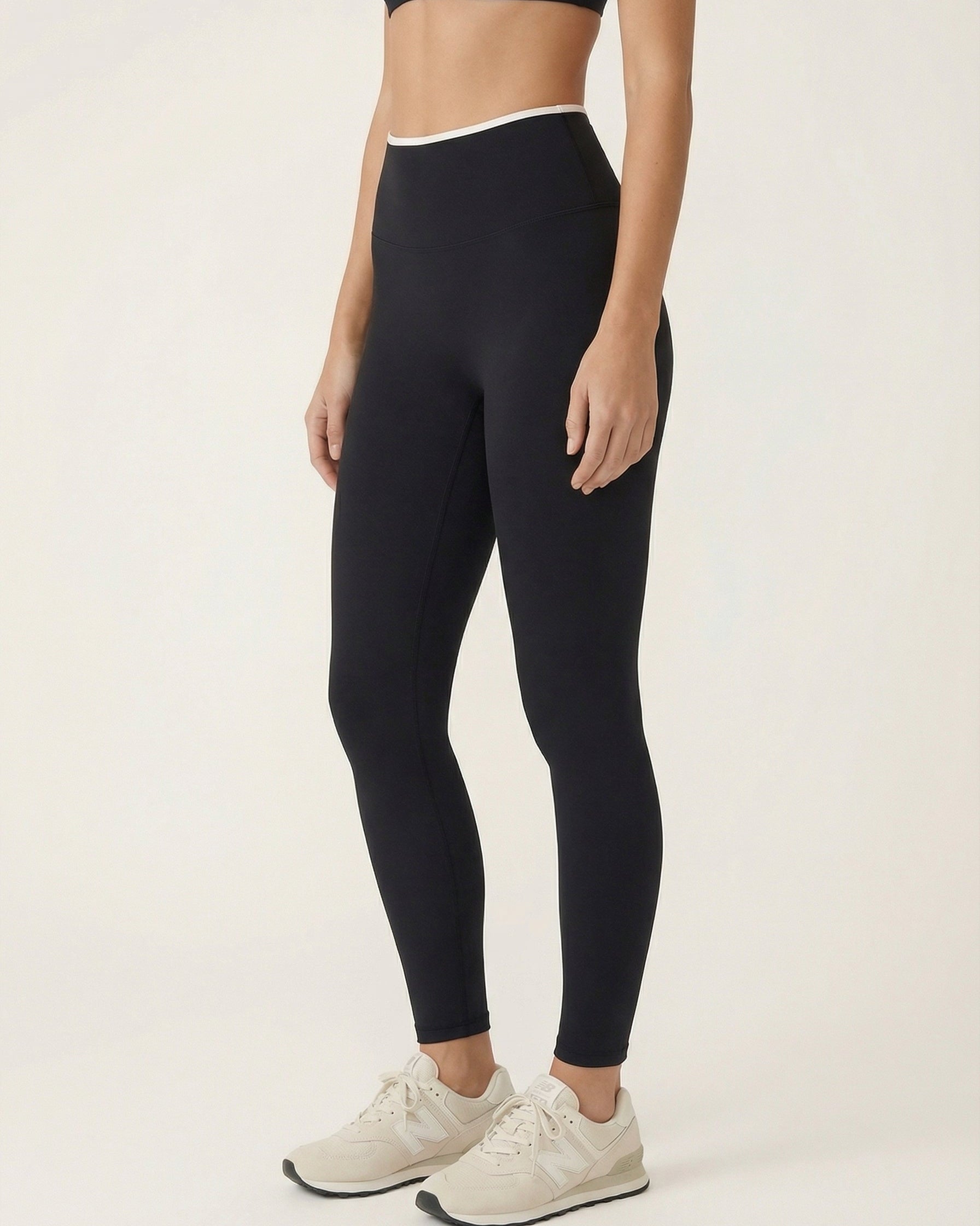 Person wearing black leggings and white sneakers on a plain background