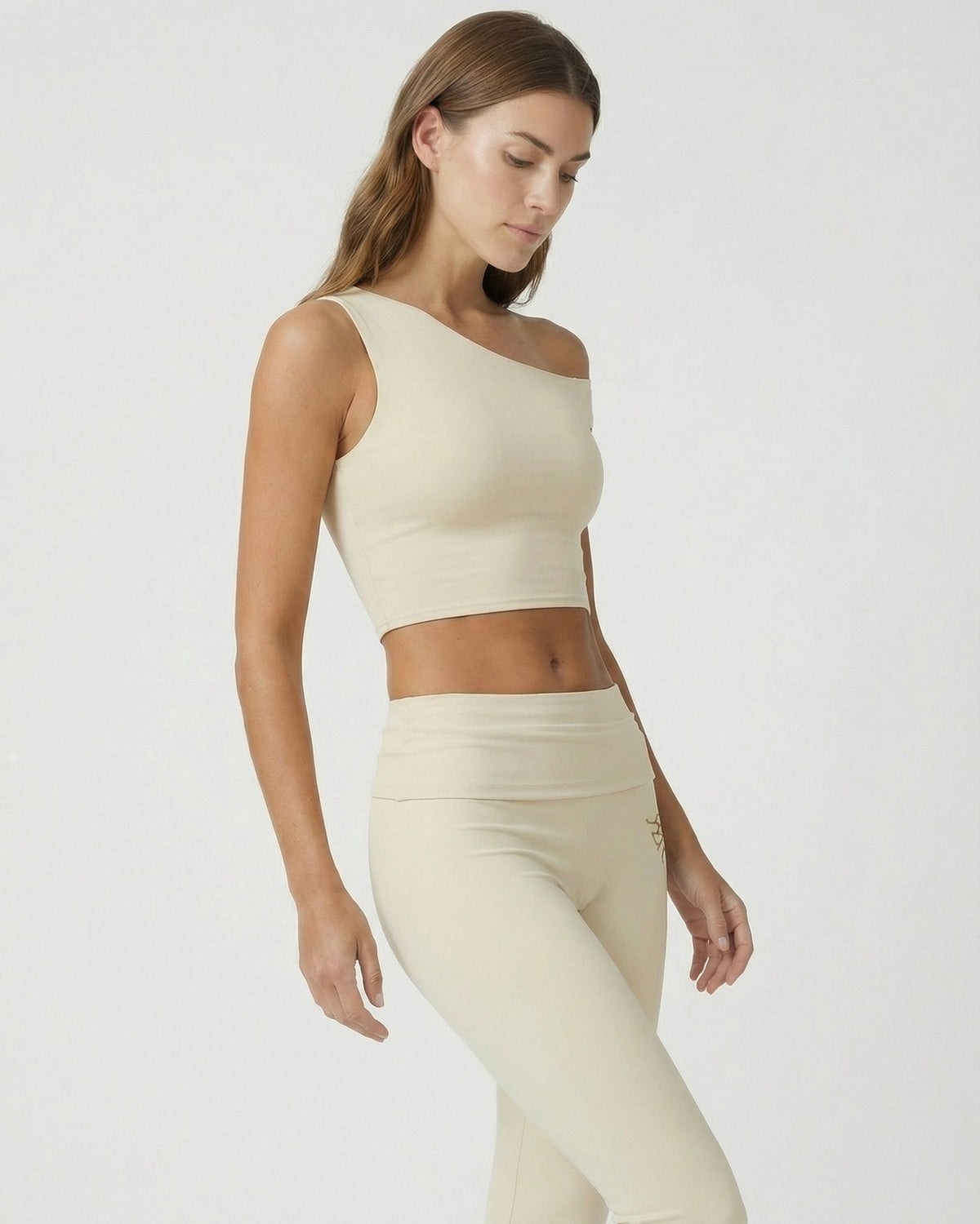 Woman wearing a beige sleeveless top and leggings on a white background