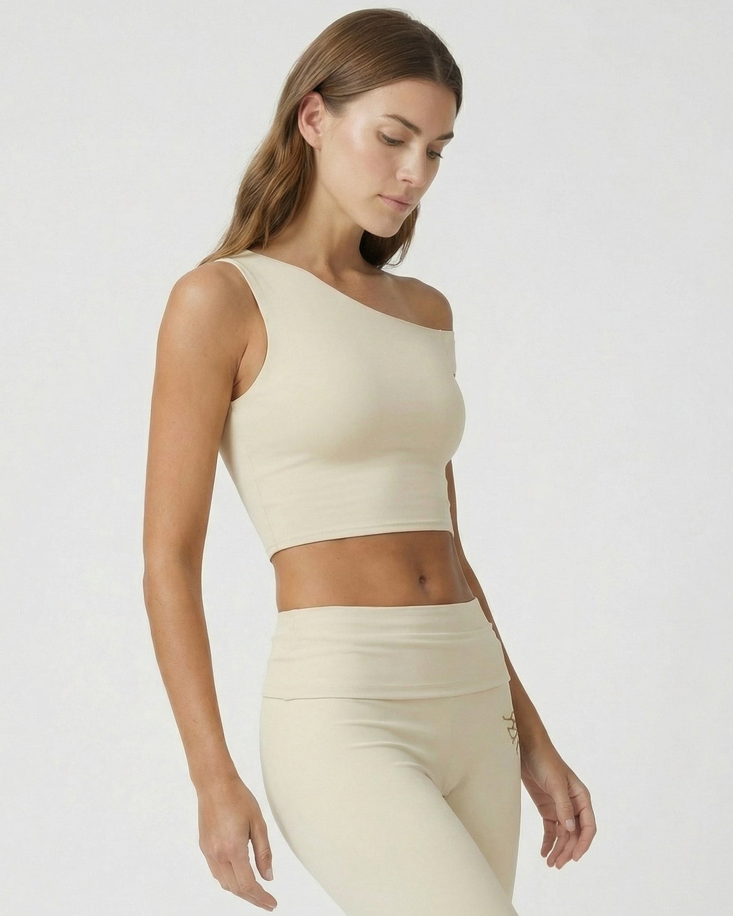 Woman wearing a beige sleeveless top and leggings on a white background
