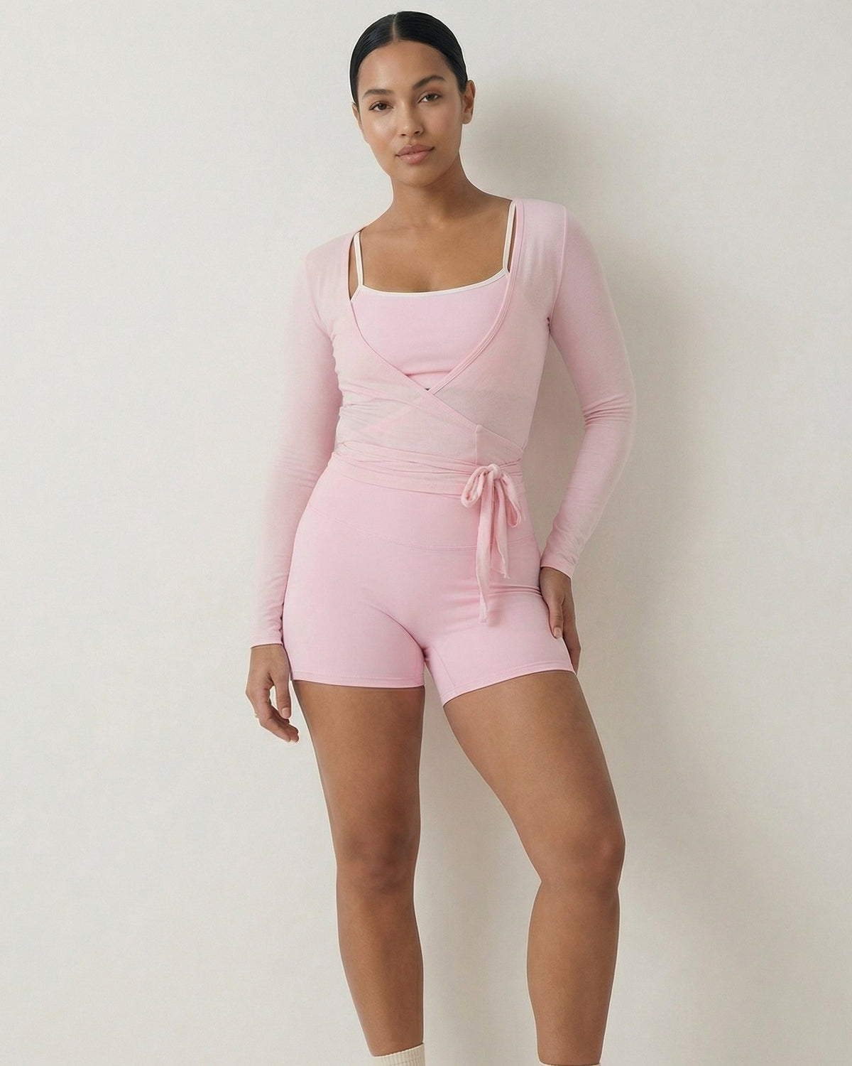 Person wearing a pink outfit with long-sleeve top and shorts on a white background