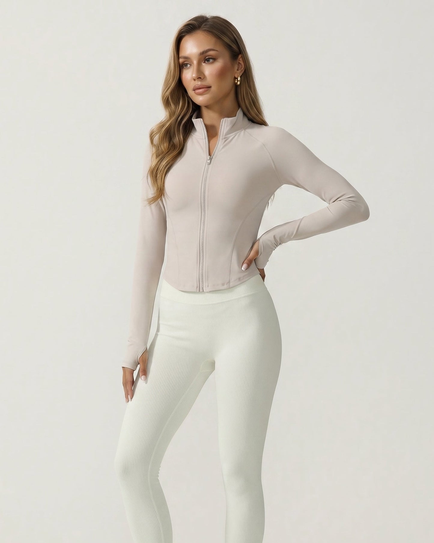 Woman wearing a light pink long-sleeve top and white pants on a white background
