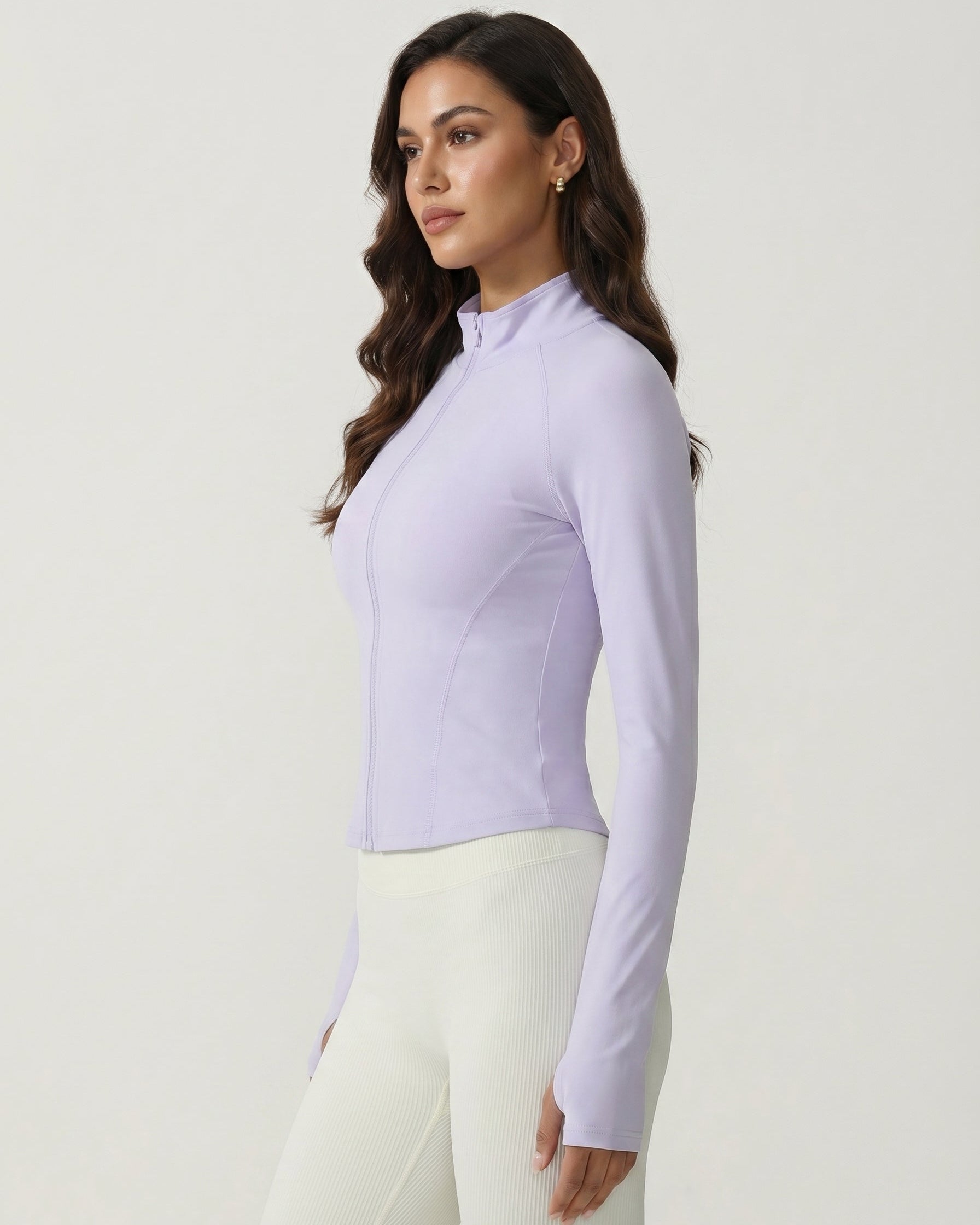 Woman wearing a light purple long-sleeve top and white pants on a plain background