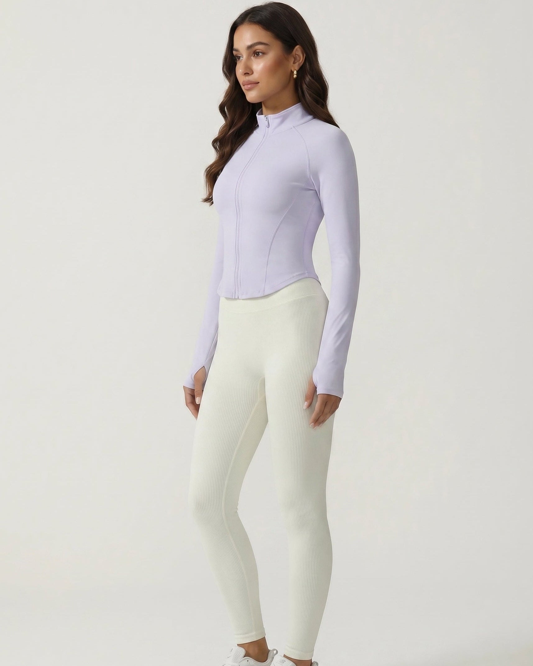 Woman wearing a light purple long-sleeve top and white leggings on a white background